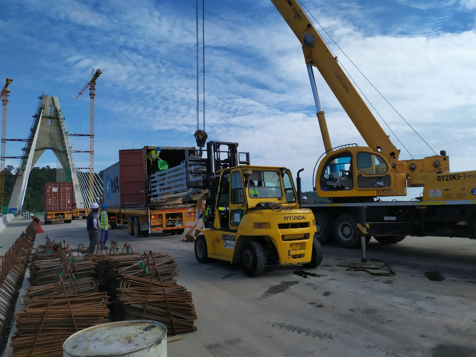 Container unloading with forklift and mobile crane at a bridge construction site
